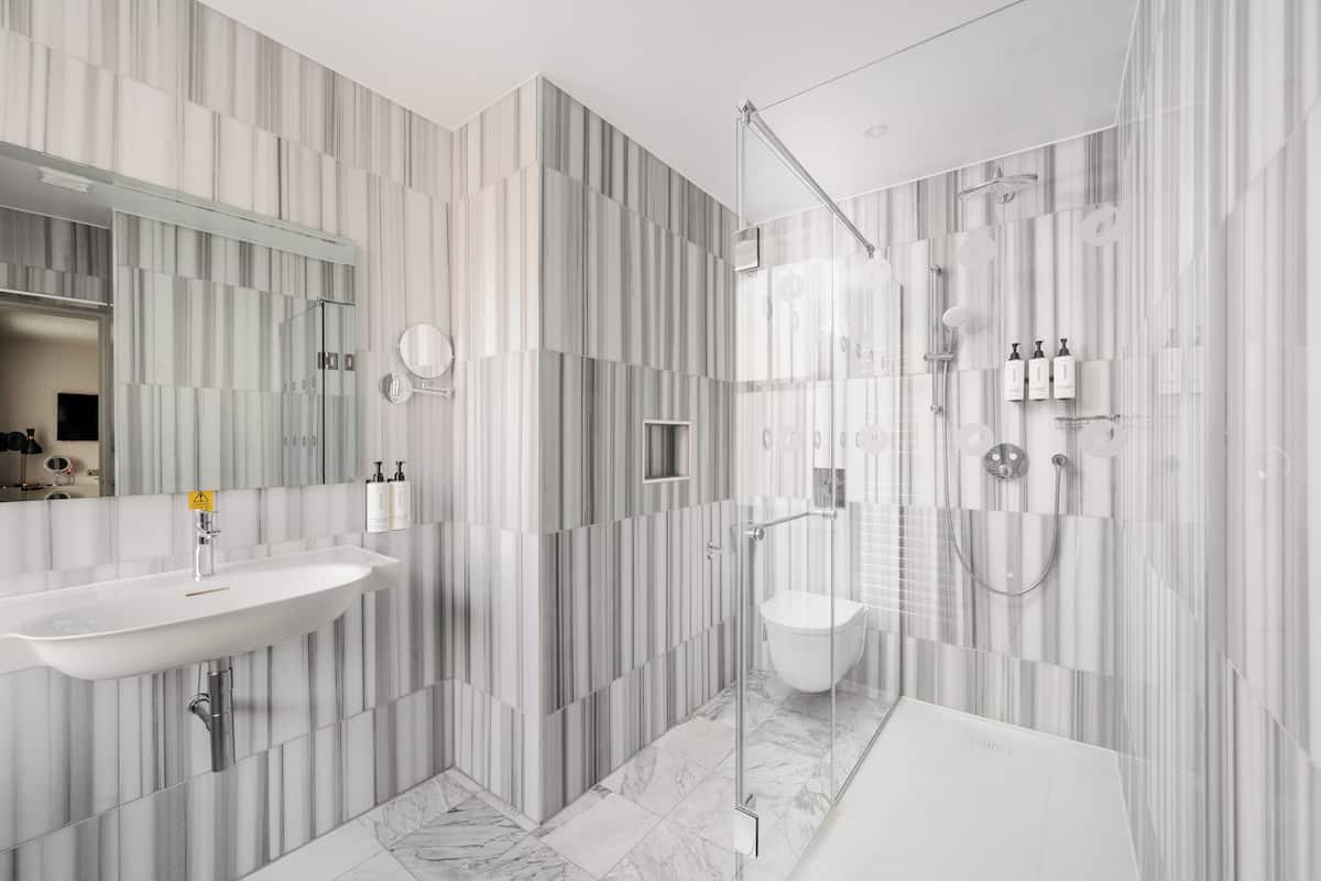 Une salle de bain moderne avec un grand lavabo, un miroir et un espace douche.