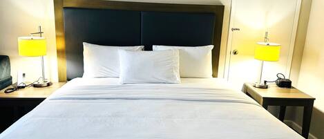 Une chambre d’hôtel avec un grand lit, deux tables de chevet, une tête de lit en bois et deux lampes de chevet.