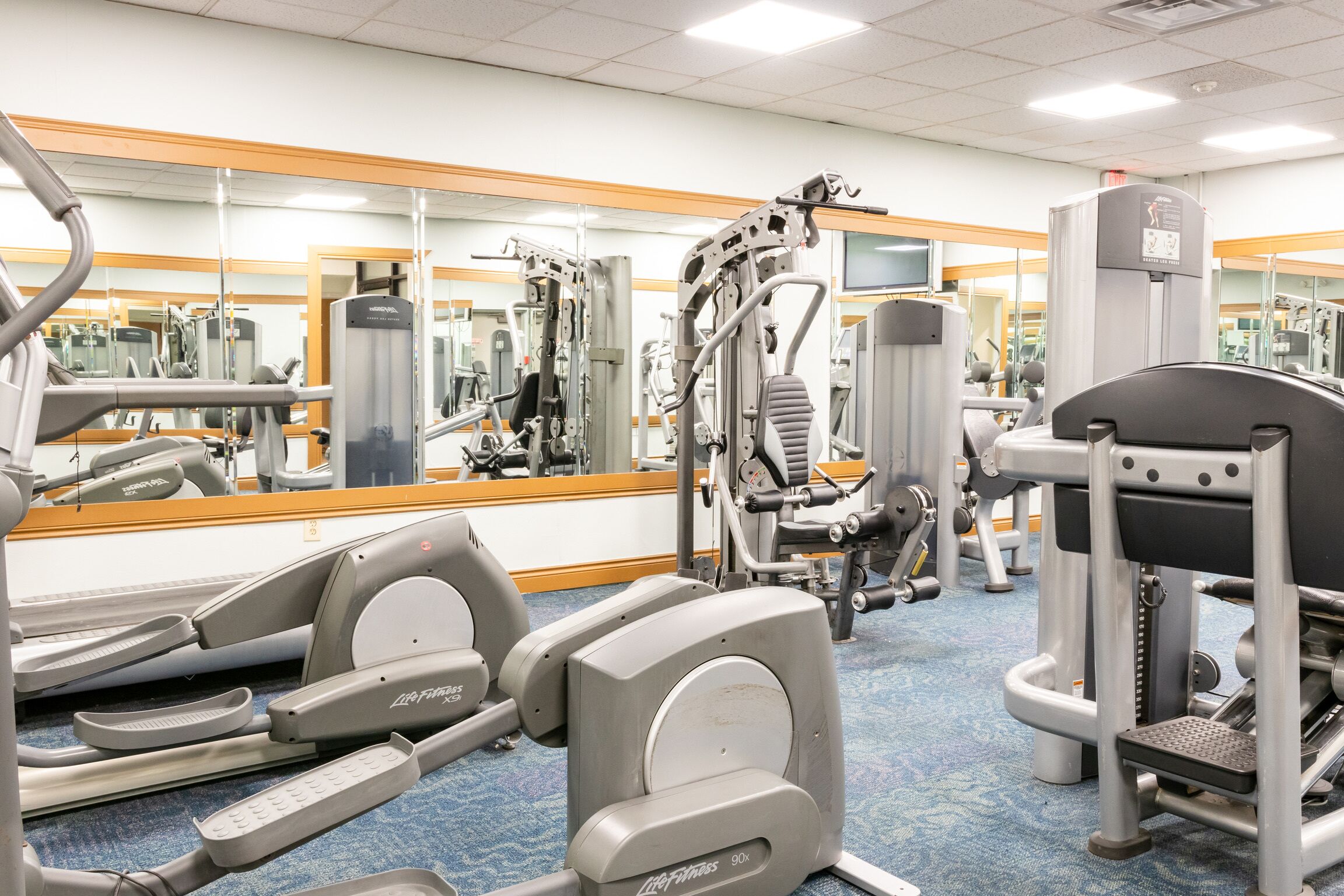 A gym with cardio machines, weight machines, and mirrors on the walls.
