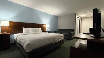 Een hotelkamer met een bed, nachtkastjes, een bureau, een stoel, een televisie en een lamp.