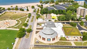 Vista aérea de una zona costera con un edificio circular, una playa y un puente.