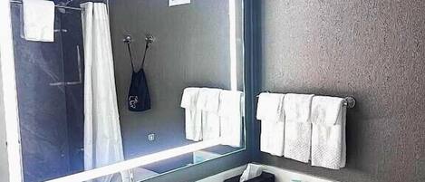 A modern bathroom with a large mirror, white sink, and a toilet.