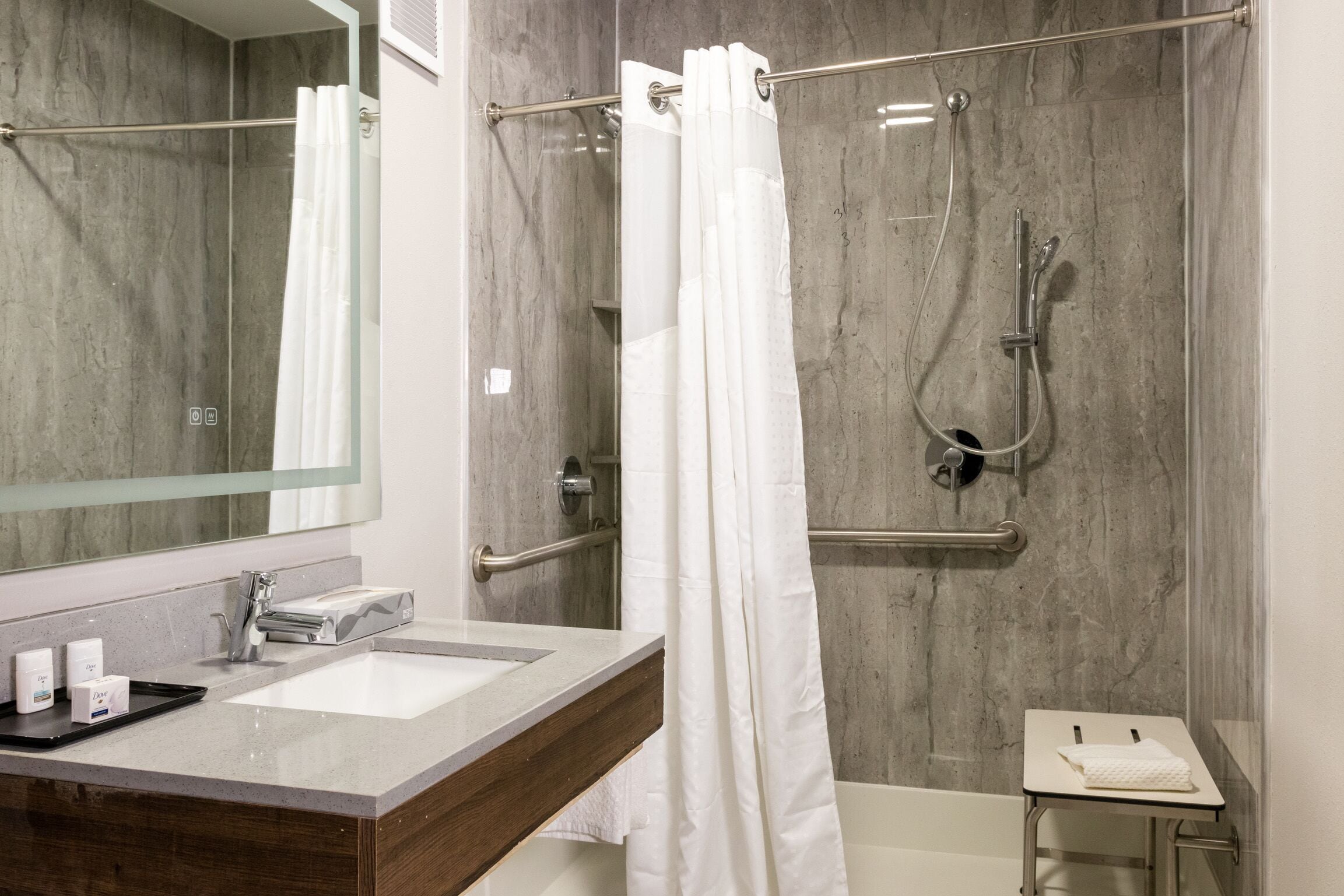 A modern bathroom with a shower, a sink, and a mirror.
