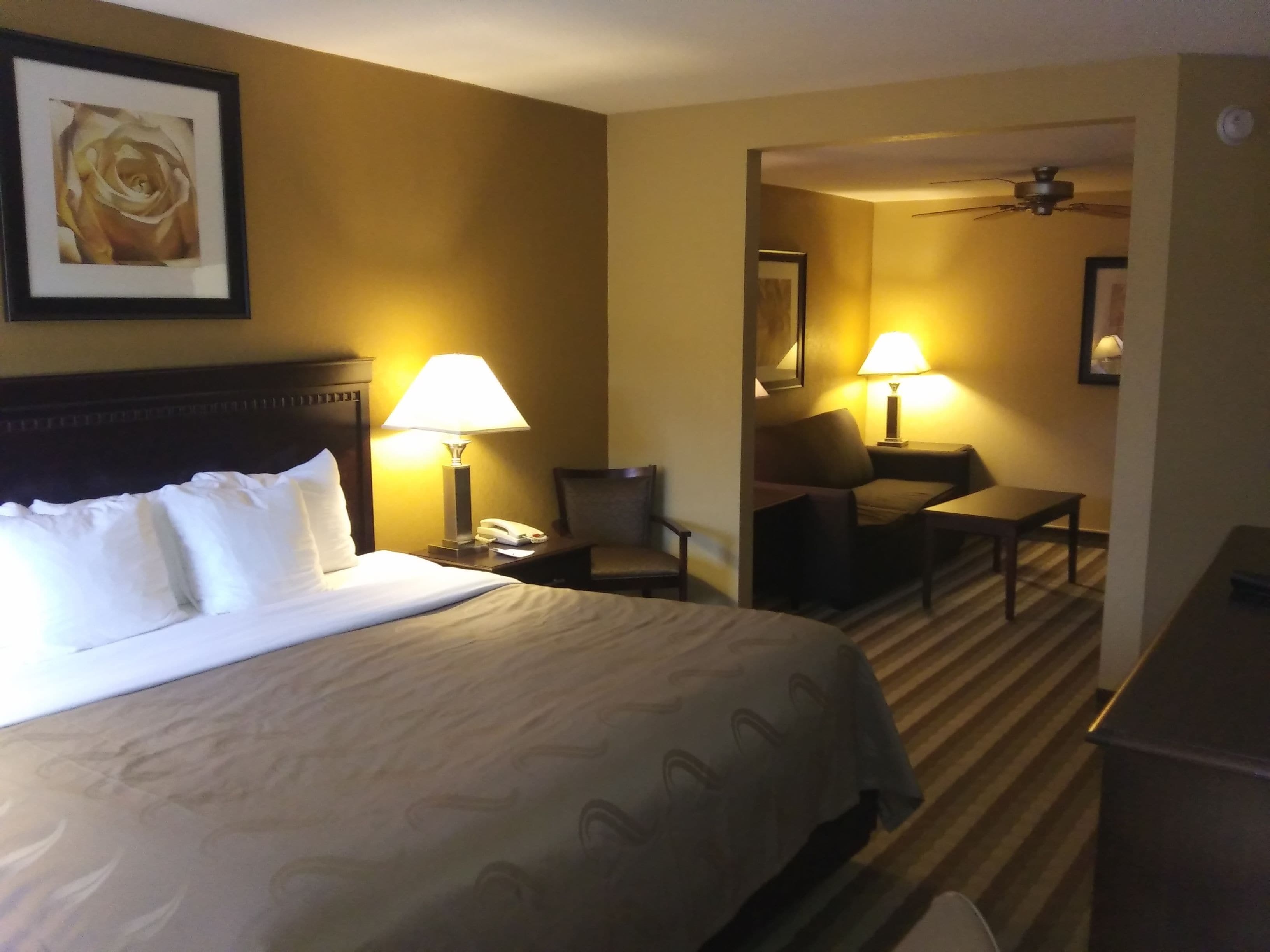 Ein Hotelzimmer mit einem großen Bett, zwei Nachttischlampen, einem Schreibtisch und einem Stuhl.