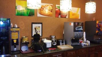 A breakfast bar with waffle and juice dispensers, a coffee maker, and a toaster.