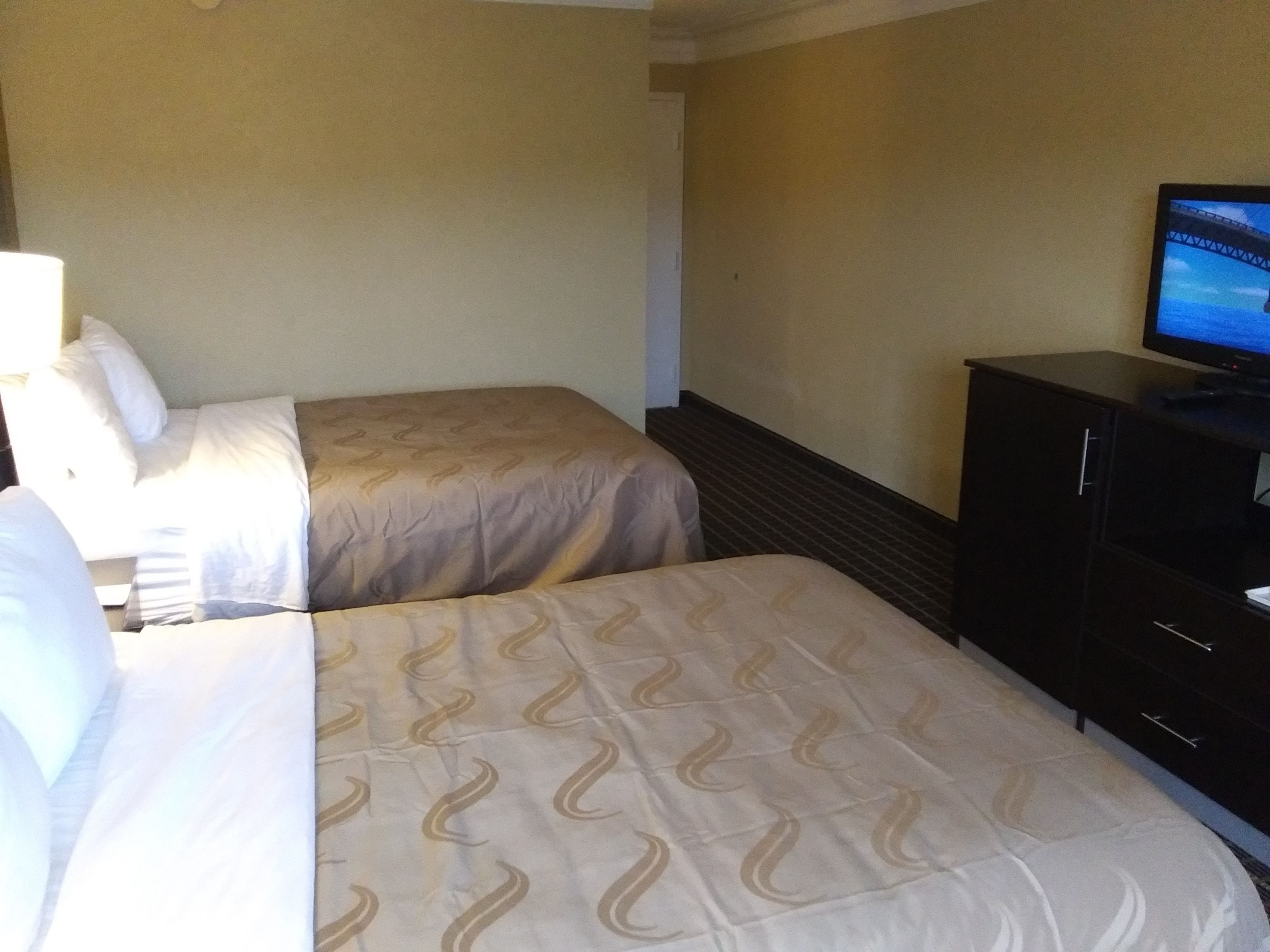 A hotel room with two beds, a television, and a dresser.