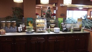 A breakfast bar with various food options, a Christmas tree, and a sign indicating 'Healthy' and 'Fresh' sections.