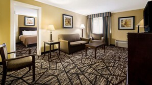 Une chambre d’hôtel avec un lit, un canapé, une chaise, une petite table et un téléviseur.