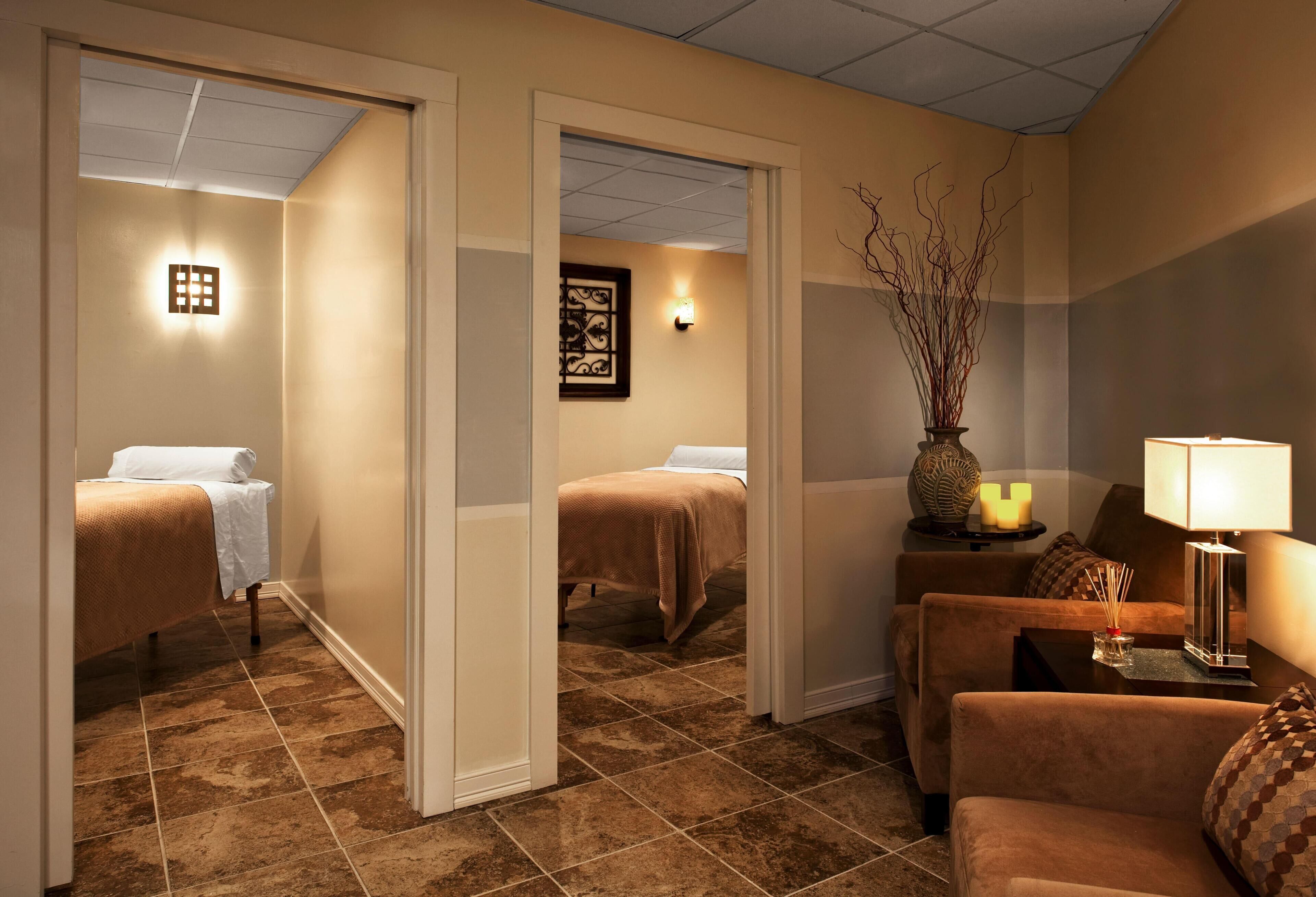 A hotel room with a bed, a sofa, a small table with a lamp, and a decorative vase.