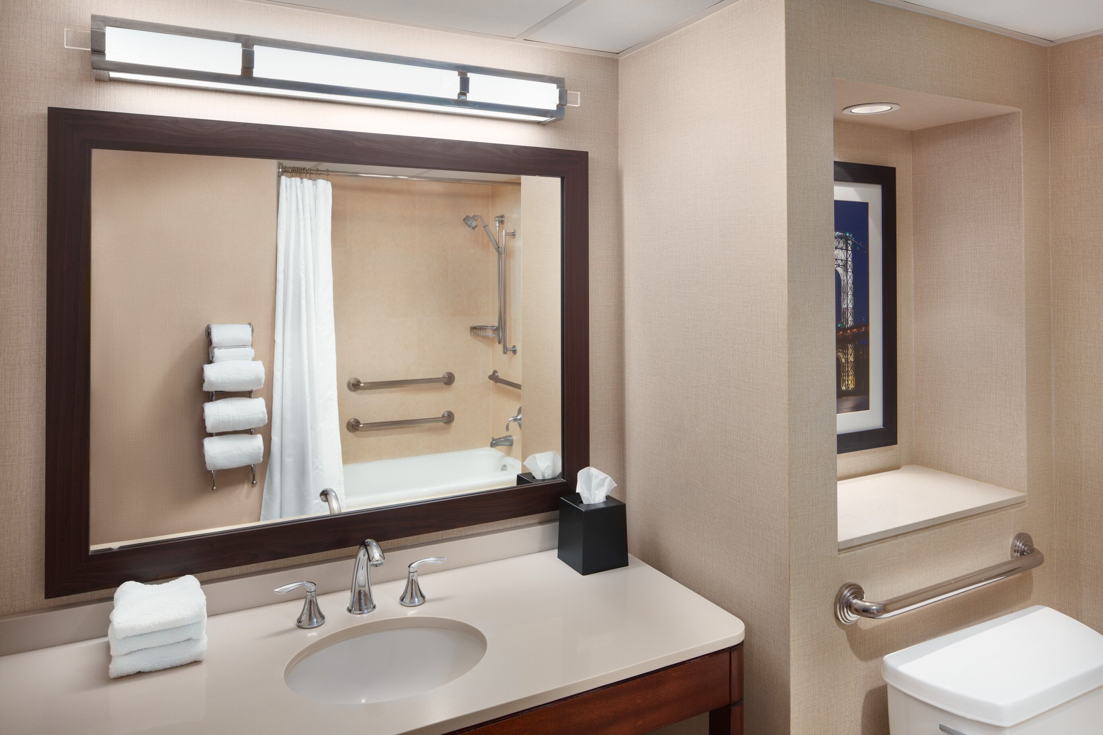 A bathroom with a large mirror, a sink, a toilet, and a shower.