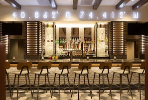A bar area with a brick wall, wooden slats, and a neon sign displaying numbers. - Dolce by Wyndham Parsippany (Parsippany)
