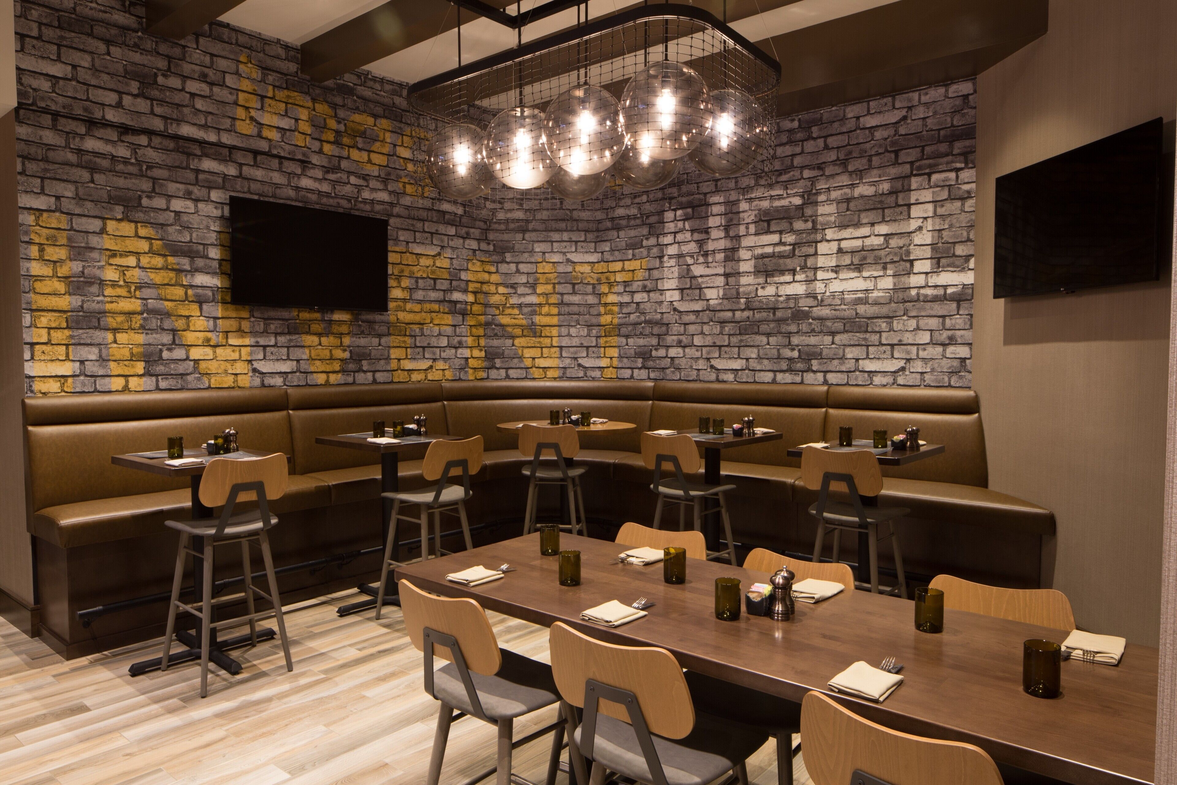 A restaurant with a brick wall, multiple seating areas, and a flat-screen TV.