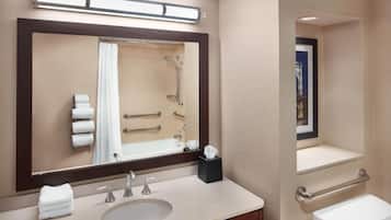 A bathroom with a large mirror, a sink, a toilet, and a shower.