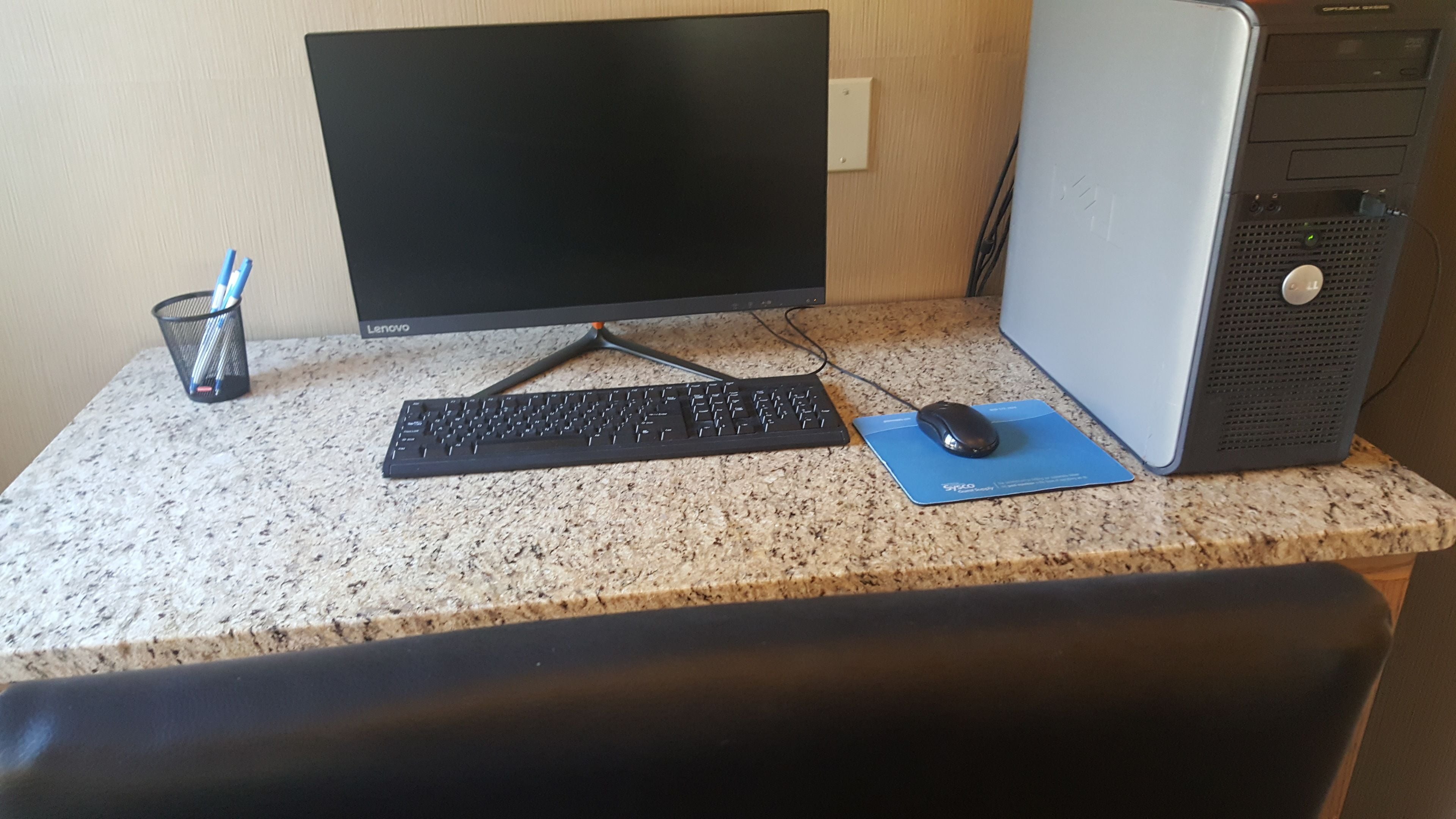 Un ordinateur de bureau comprenant un écran, un clavier, une souris et une tour d’ordinateur, le tout installé sur un comptoir en granit.