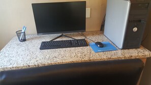 Equipo de computadora de escritorio con monitor, teclado, ratón y torre sobre una encimera de granito.
