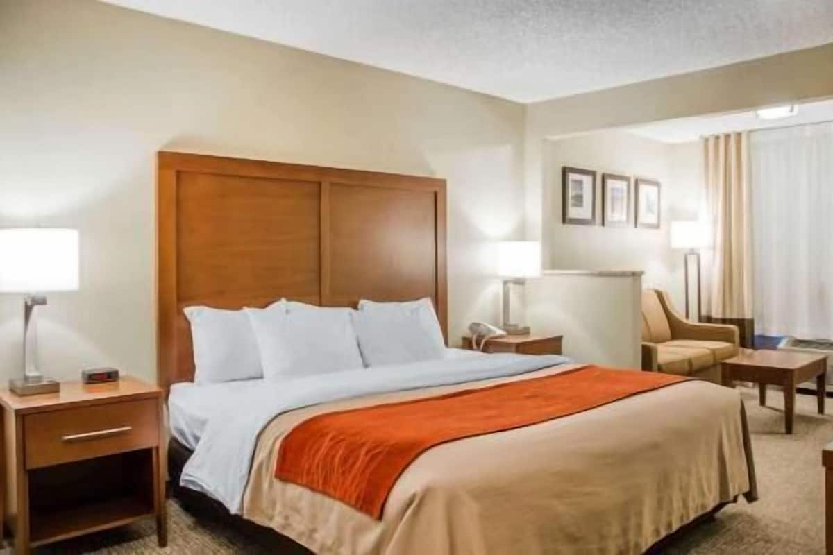 A hotel room with a bed, a nightstand, a chair, and a desk.