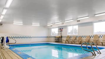 Piscina interna com piso ladrilhado, cadeira de salva-vidas e sinal de alerta na parede.