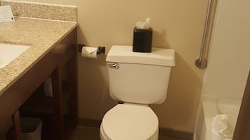 A small bathroom with a toilet, a sink, and a framed picture on the wall.