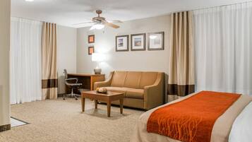 Une chambre d’hôtel équipée d’un lit, d’un canapé, d’un bureau, d’une chaise et d’un ventilateur de plafond.