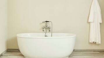 A modern bathroom with a freestanding bathtub, a towel rack, and a tiled floor.