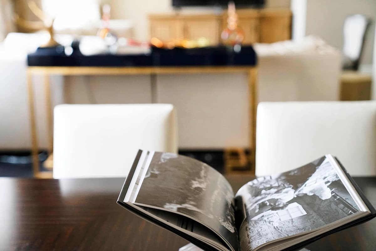 Un libro abierto sobre una mesa de madera en una habitación con una cocina al fondo.
