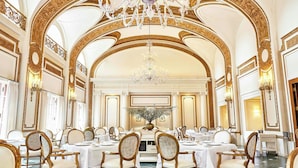 Un gran comedor con detalles dorados ornamentales, candelabros y un arreglo floral central.
