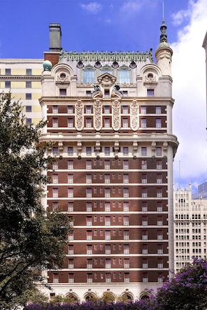 A multi-story hotel with a classic architectural design, featuring ornate balconies and a prominent tower.