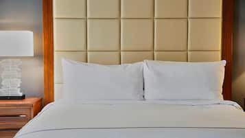 A bed with a tufted headboard, a bedside table with a lamp, and a stack of books.