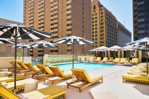 Una piscina al aire libre, camas de piscina con cargo, sombrillas