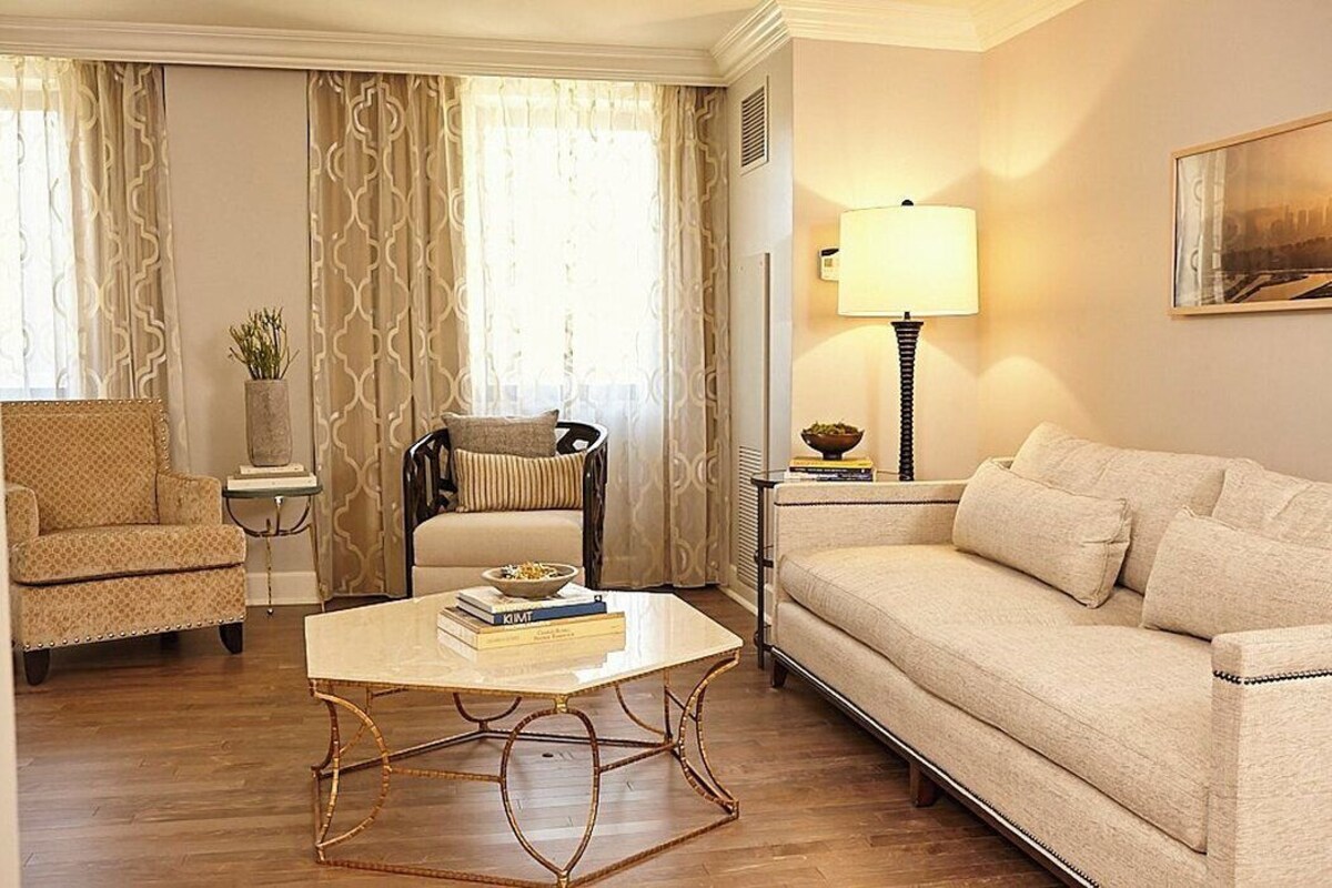 A living room with a sofa, armchair, coffee table, lamp, and a painting on the wall.