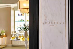 Interior de un spa con una pared de mármol que muestra 'SPA ADOLEPHUS DALLAS'.