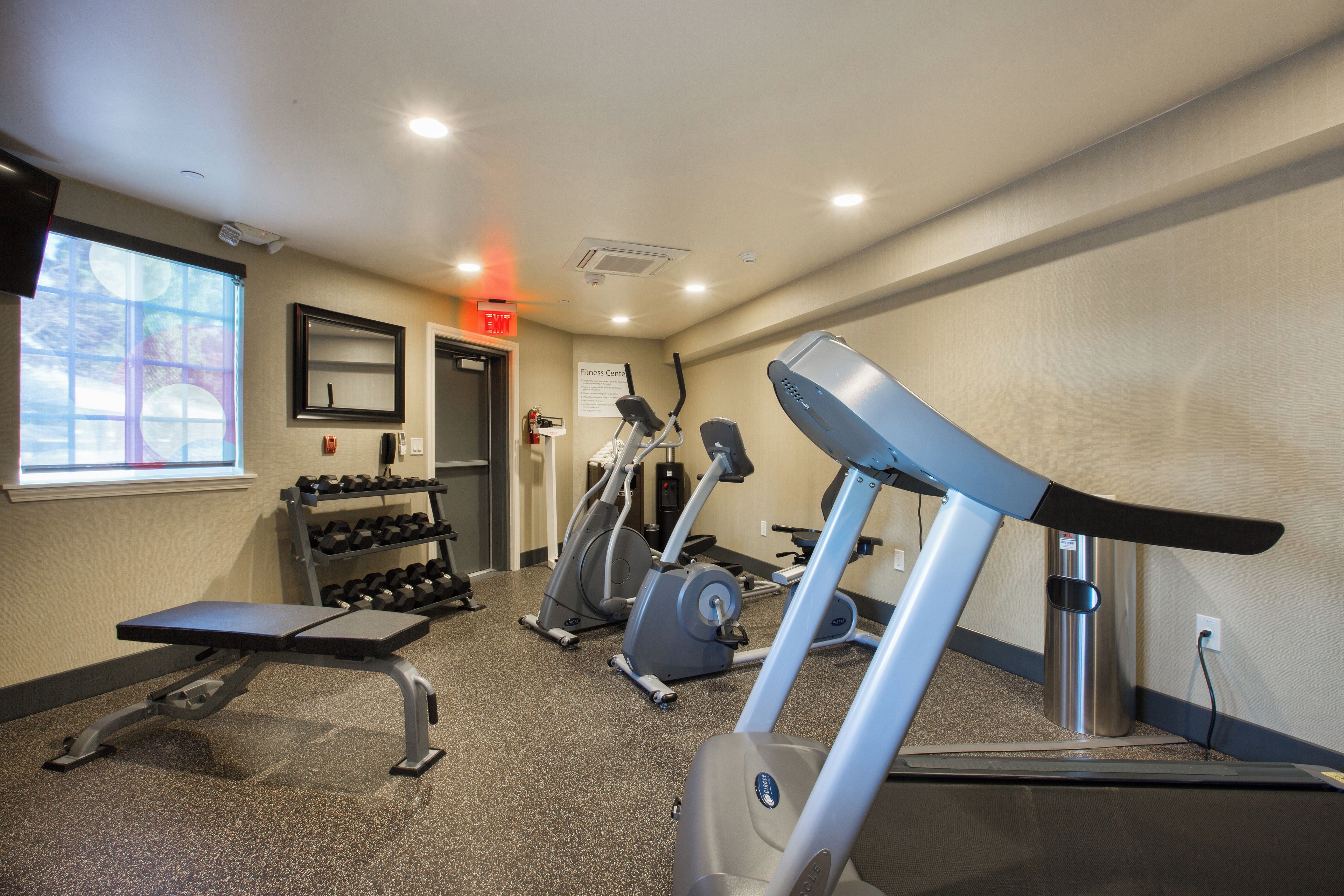 A fitness center with treadmills, dumbbells, and a bench.