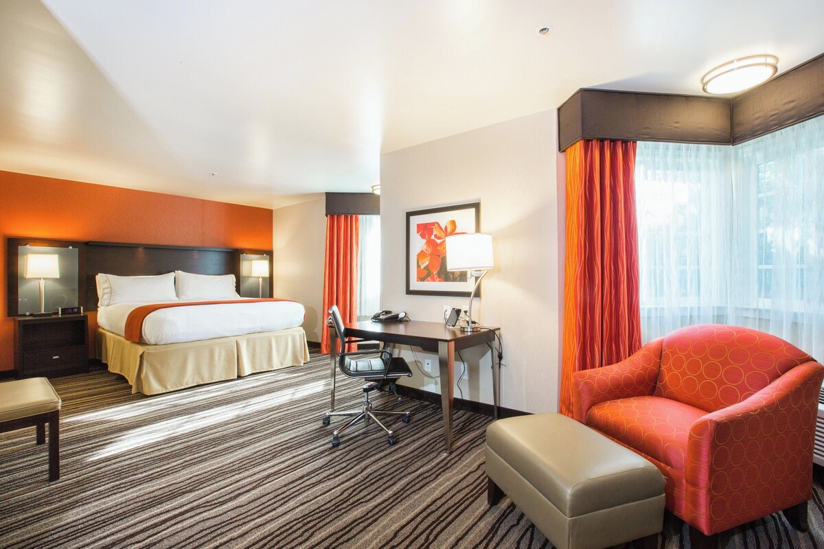 Una habitación de hotel con cama, escritorio, silla y una mesita.