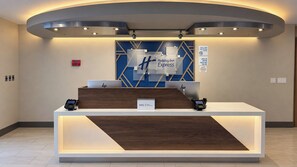 A hotel reception desk with a modern design, featuring a digital check-in system, a sign for Holiday Inn Express, and a sign indicating a 100% non-smoking property. - Holiday Inn Express Mountain View - S Palo Alto by IHG (Mountain View)