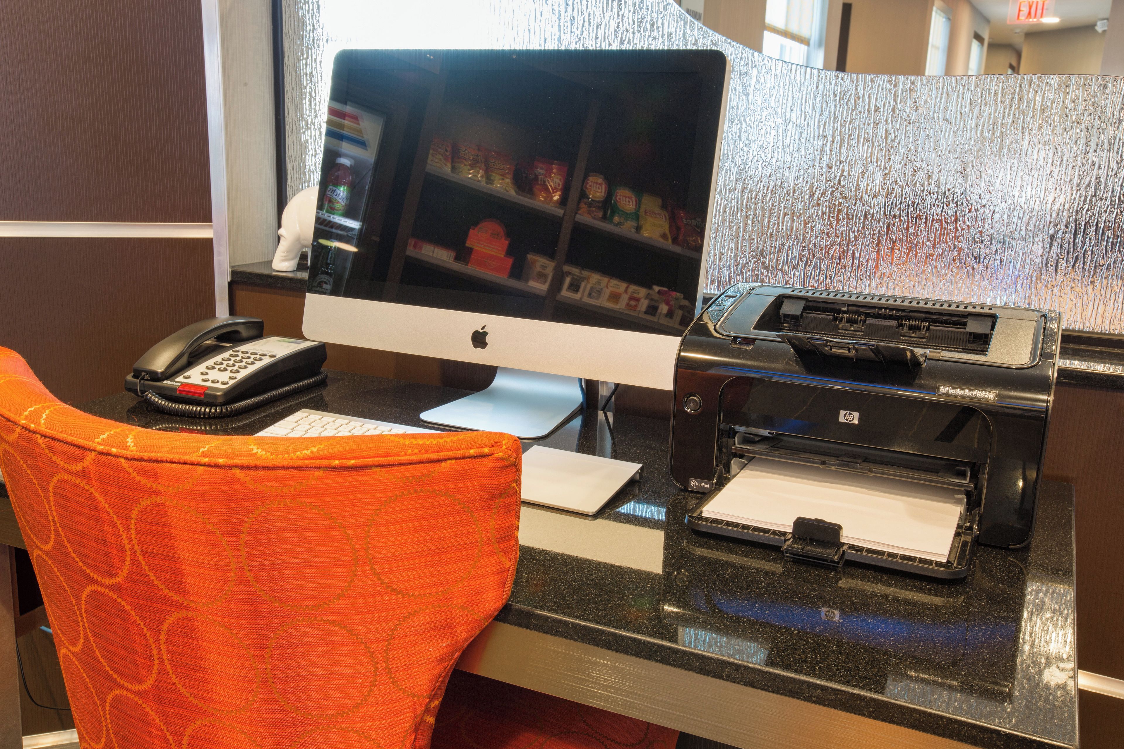 A hotel reception desk with a desktop computer, a telephone, and a printer.