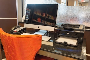 A hotel reception desk with a desktop computer, a telephone, and a printer.