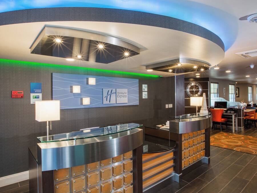 Un'area reception di un hotel dal design moderno, con una scrivania della reception, un orologio e un'area salotto con tavoli e sedie.