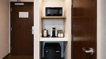 A kitchenette with a microwave, coffee maker, and a trash bin.