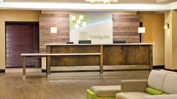 Un comptoir d’accueil avec un panneau décoratif en bois, un lustre et une enseigne indiquant « Holiday Inn ».