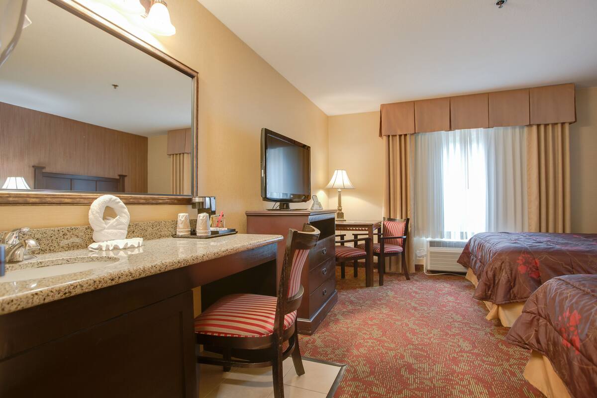 Ein Hotelzimmer mit Bett, Schreibtisch, Stuhl, Fernseher und Badezimmer.