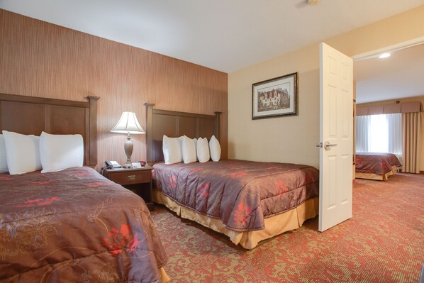 A hotel room with two beds, a nightstand, a lamp, and a framed picture on the wall.