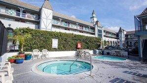 A hotel pool area with two pools, outdoor seating, and a hedge. - Castle Inn and Suites (Anaheim)