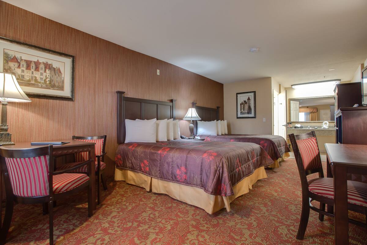 Ein Hotelzimmer mit zwei Betten, einem Schreibtisch und Stühlen.