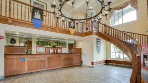 Eine geräumige Lobby mit einem Holzbüro, einer Uhr und einer Treppe.