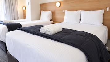 A hotel room with two beds, a wooden headboard, and a large window with curtains.