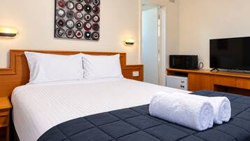 A hotel room with a bed, a television, a microwave, and a small refrigerator.