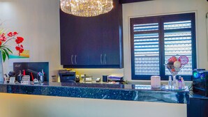 A modern kitchen with a central island, dark cabinets, a large window with blinds, and a chandelier. - Abbotsleigh Motor Inn (Armidale)