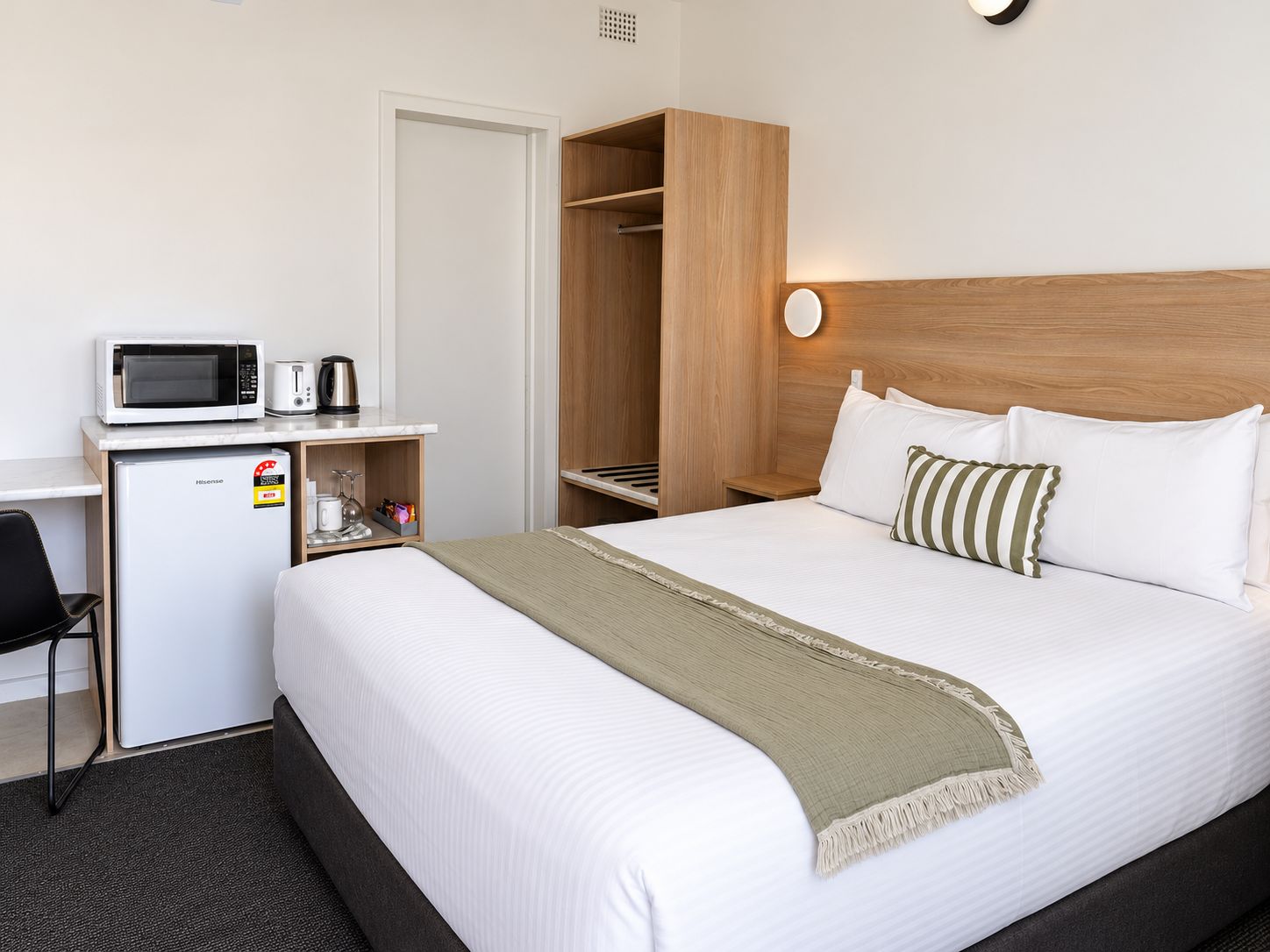 Une chambre d’hôtel comprenant un lit, un bureau avec un micro-ondes, un mini-réfrigérateur et une armoire.