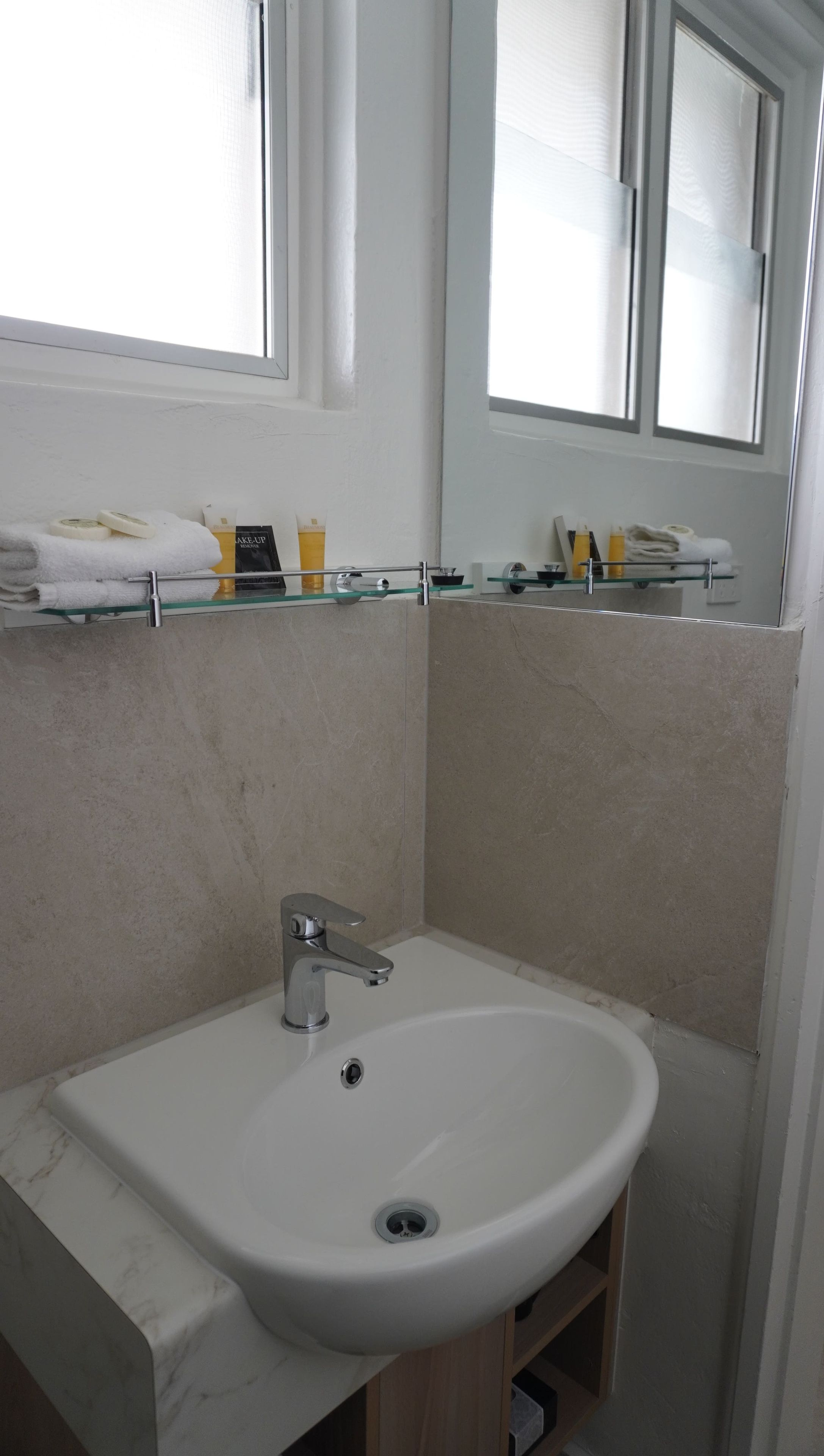 Un baño con un lavabo blanco, un espejo y una ventana.