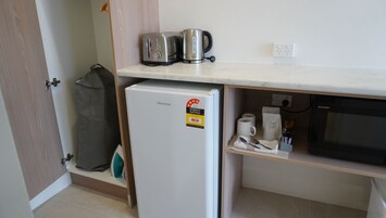Una cocina compacta con un refrigerador Hisense, un microondas Sharp y una tetera sobre la encimera.